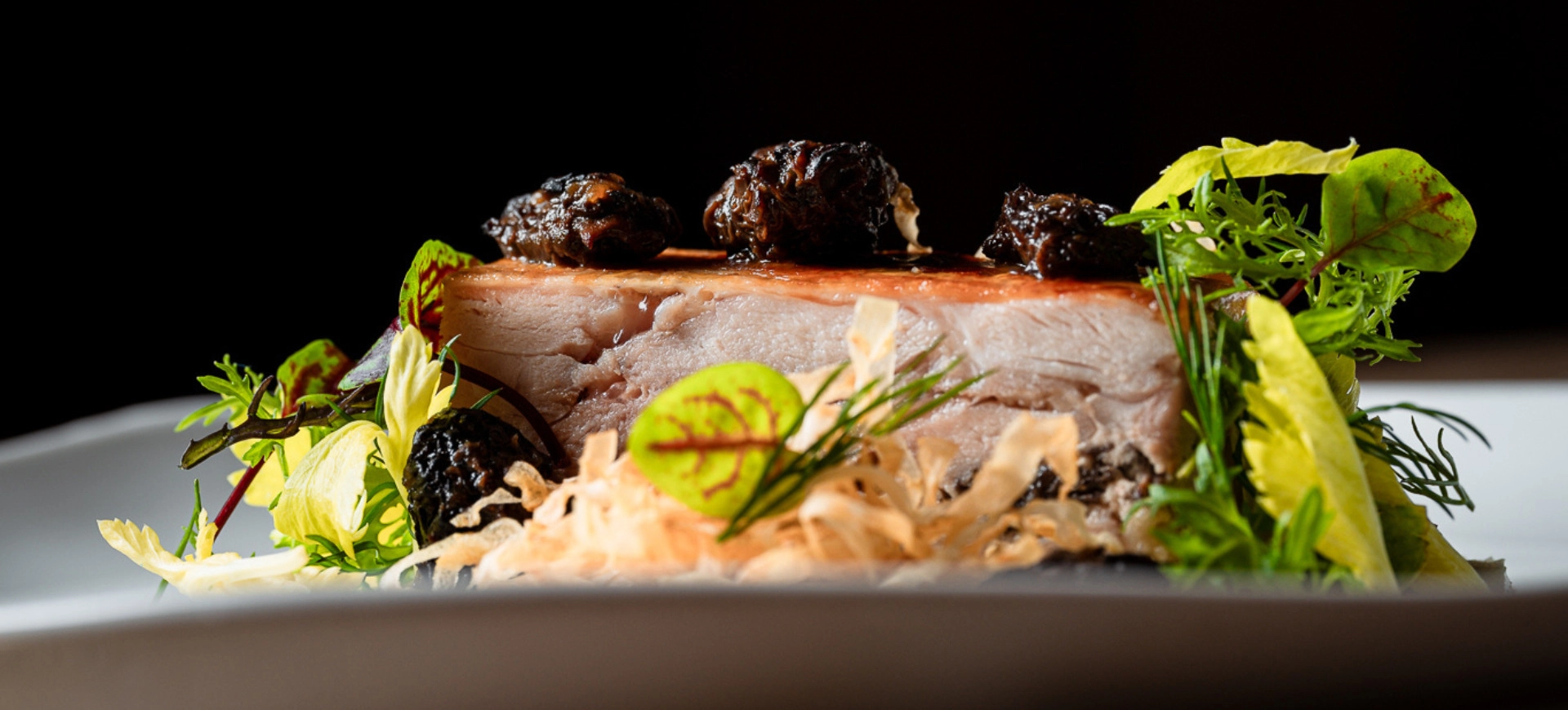 Un plat gastronomique raffiné, mettant en valeur une pièce de viande fondante, agrémentée de condiments et d’herbes fraîches, dressée avec élégance.