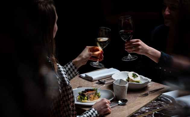 Deux personnes partageant un dîner dans une ambiance immersive et sensorielle, plongées dans l’obscurité totale.