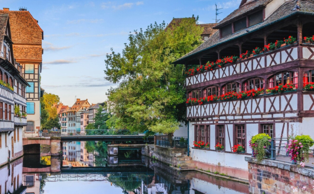 Vue pittoresque du quartier de la Petite France à Strasbourg, avec ses maisons à colombages typiques et son canal reflétant l'architecture alsacienne.